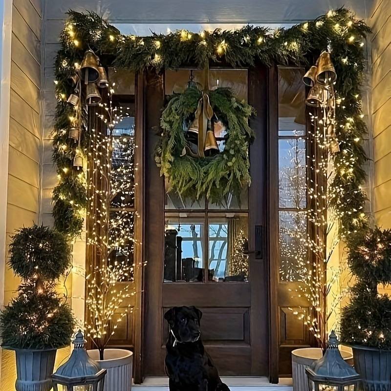 Front entryway covered in Christmas decorations, with garlands, a wreath with golden bells, and twinkling lights for a festive welcome.